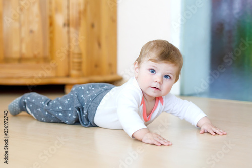Little cute baby girl learning to crawl. Healthy child crawling in kids room. Smiling happy healthy toddler girl. Cute toddler discovering home and learning different skills © Irina Schmidt
