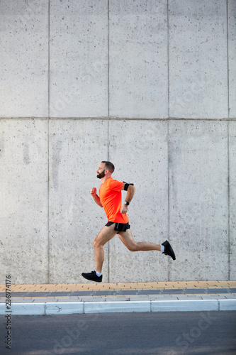 Young bearded man running on the street. Healthy lifestyle concept.