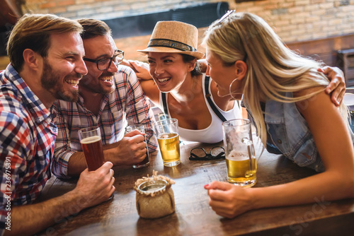 Young cheerful people in the beer pub drinking and having good time