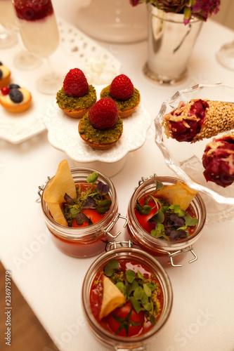 Delicious tartlets filled with fruits. Dessert in glass jags. Table set.