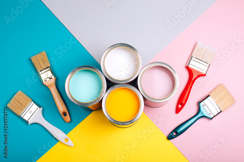 Fototapeta Naklejka Na Ścianę i Meble -  Four open cans of paint with brushes on bright background. Yellow, white, pink, turquoise colors of paint. Top view.