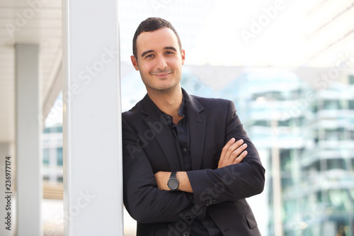 businessman leaning against post outside in the city