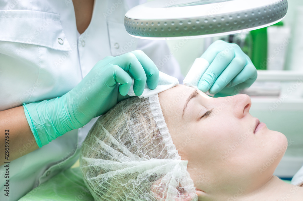 Facial cleansing by a beautician in a beauty salon. Face close-up Facial cleansing by a beautician in a beauty salon. Face close-up