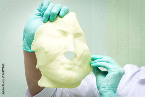 Beautician holds in his hands the shot alginate mask from his face. Close up photo