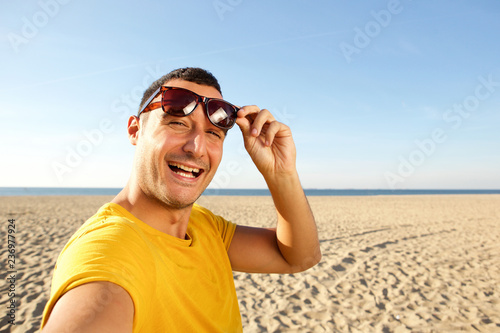 Close up happy man taking selfie at beach © mimagephotos
