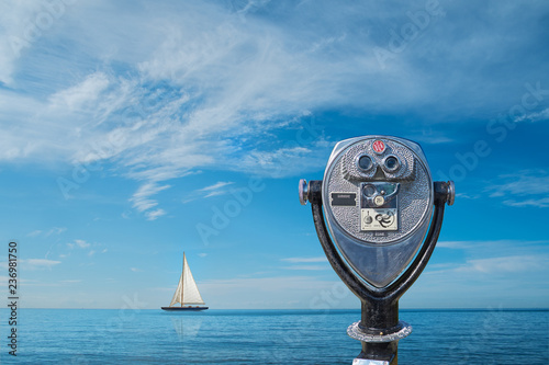 Binocular viewer overlooking sea with yacht on horizon