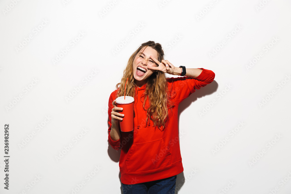 Image of pretty woman 20s wearing red sweatshirt drinking soda from paper cup using straw, isolated over white background Image of pretty woman 20s wearing red sweatshirt drinking soda from paper cup using straw, isolated over white background