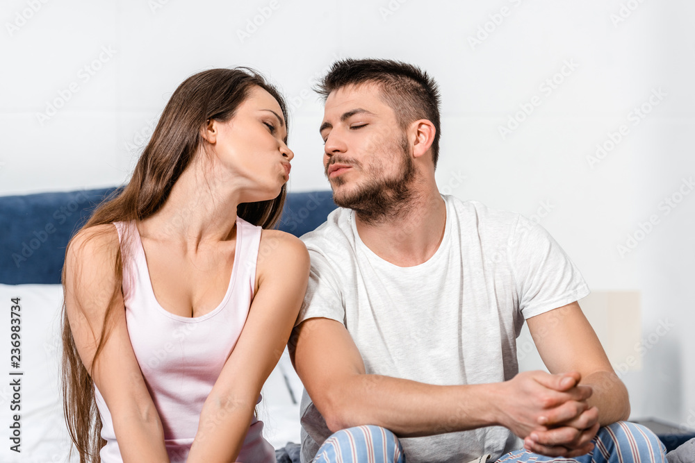 girlfriend and boyfriend in pajamas going to kiss on bed in bedroom girlfriend and boyfriend in pajamas going to kiss on bed in bedroom
