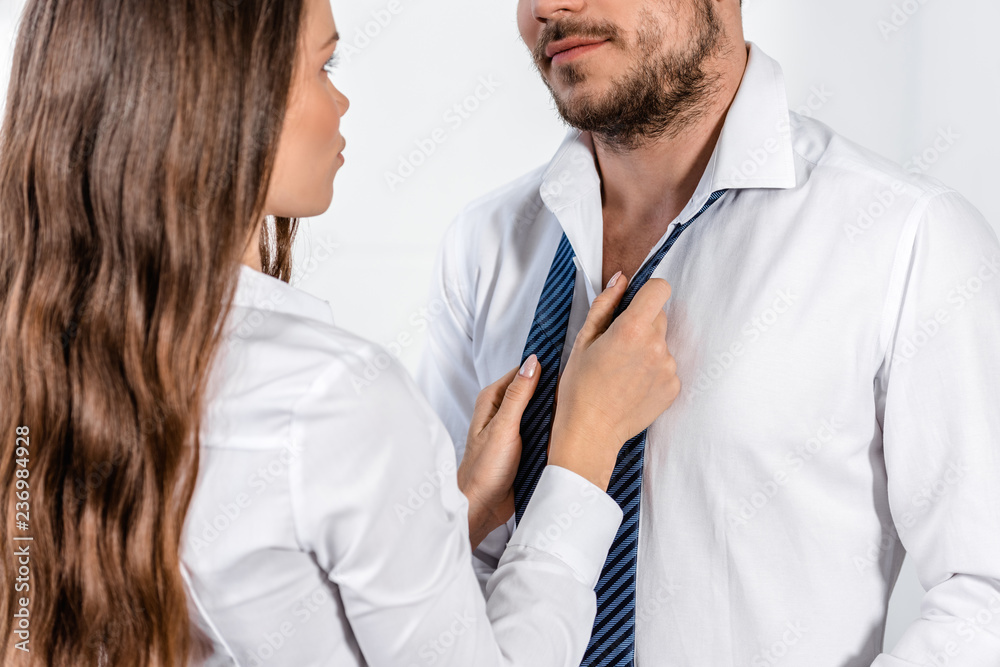 cropped image of girlfriend tying boyfriend tie in morning at home, social role concept cropped image of girlfriend tying boyfriend tie in morning at home, social role concept