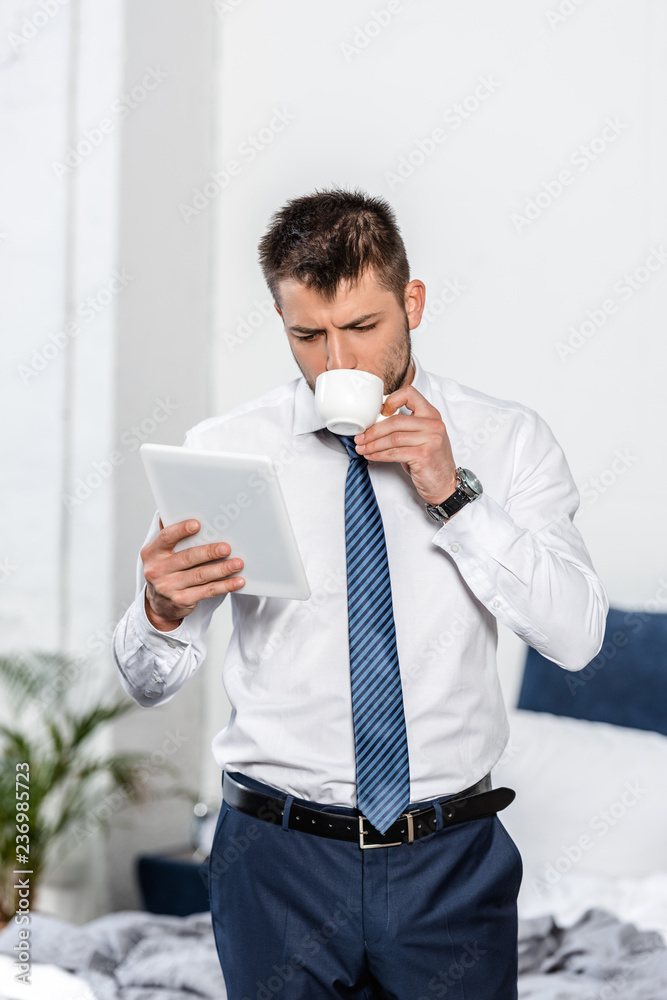 handsome man drinking coffee and using tablet in morning in bedroom handsome man drinking coffee and using tablet in morning in bedroom