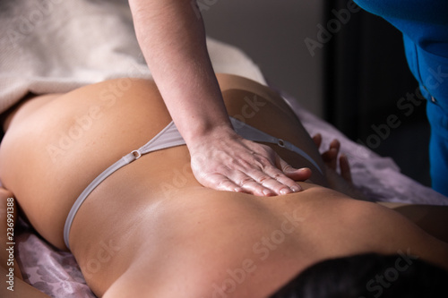 Massage session. A masseuse gives a massage treatment. Back massage. Pressing on the loin