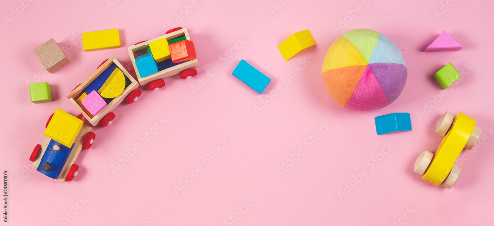 Toys background. Baby kids toys frame with toy cars, colorful wooden cubes on pink background Toys background. Baby kids toys frame with toy cars, colorful wooden cubes on pink background