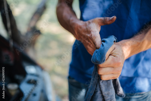 Man wipes his hands with a cloth in front of car