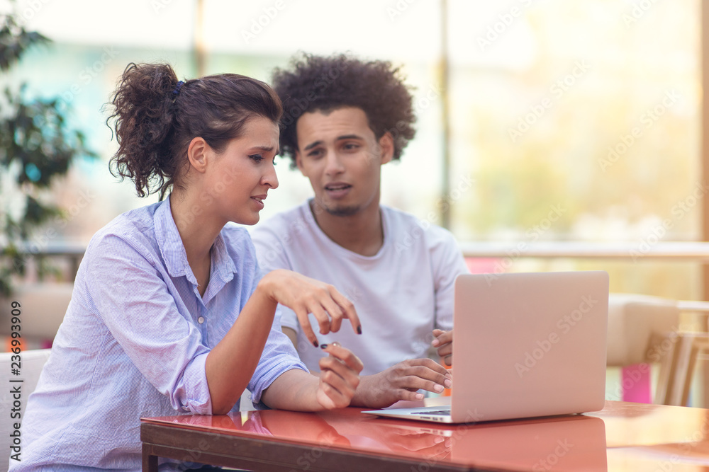 Interracial couple using tablet computer in coffee shop