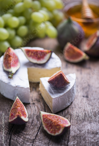Homemade fresh cheese with sweet honey and ripe fruits on a wooden background.