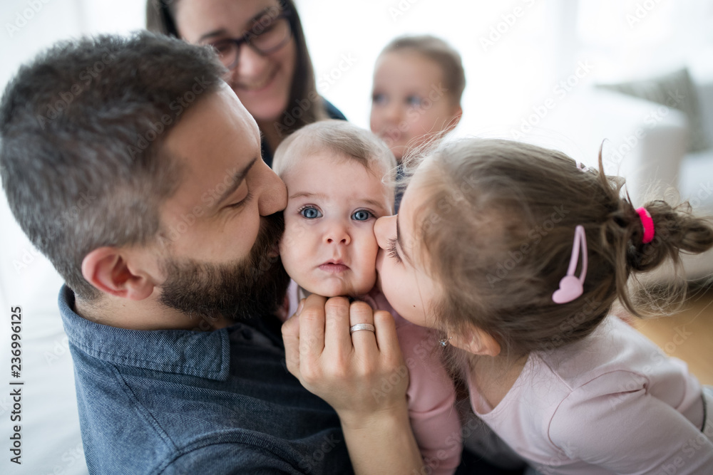 A portrait of young family with small children sitting indoors on a sofa, having fun. A portrait of young family with small children sitting indoors on a sofa, having fun.