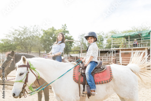 Girl And Mother Sitting On Horses During Therapy