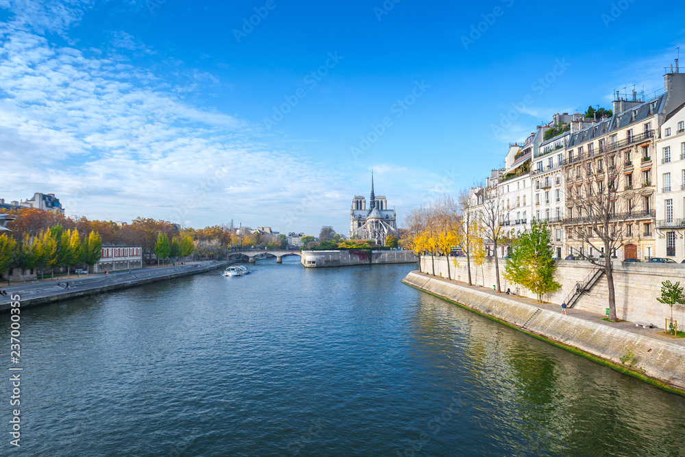 Cathedral of Notre Dame de Paris sunny autumn afternoon. Embankment of the Seine River. The natives and tourists take a walk and relax in warm weather. Blurred, unrecognizable faces. Paris. France.