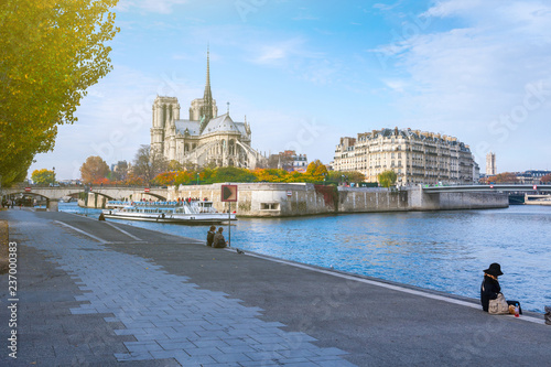 Cathedral of Notre Dame de Paris at sunny autumn afternoon. Embankment of the Seine. Boat on scenic route. Tourists a walk and relax in warm weather. Blurred unrecognizable faces. Paris. France. © Sodel Vladyslav