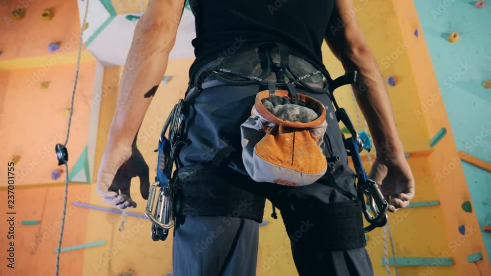 Equipped man being ready to start clambering a gym wall in a backside view Equipped man being ready to start clambering a gym wall in a backside view