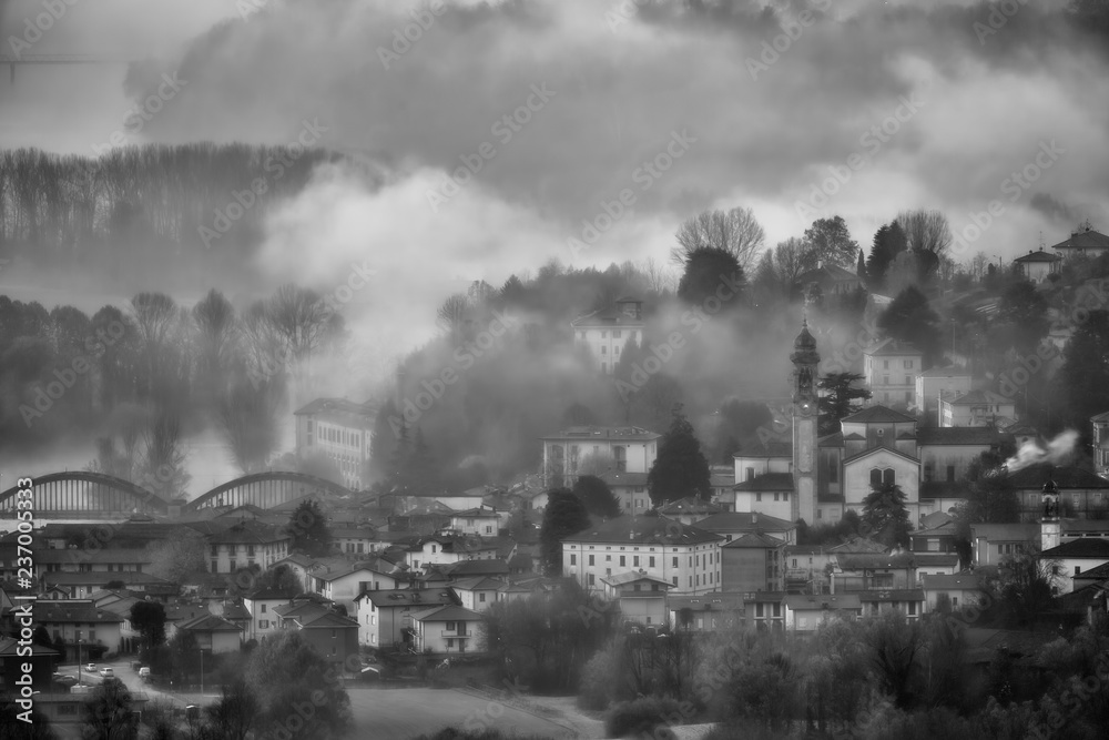 Alba con nebbia sul paesi di Brivio, Lombardia, Italia