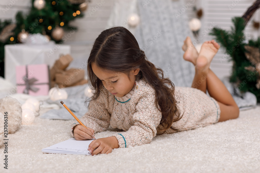 Fototapeta premium Cute child girl writing letter to Santa Claus at home