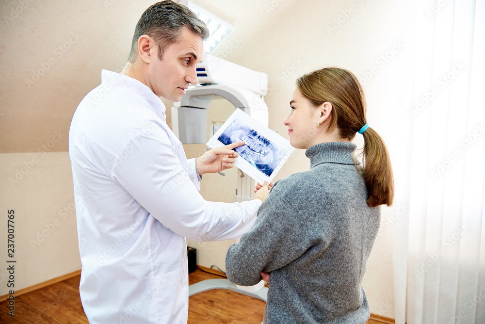 Fototapeta premium The doctor shows the patient an x-ray image. Computer diagnostics. dental tomography