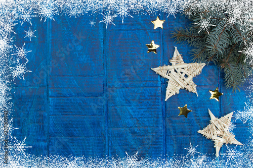 Christmas background. gold stars decorations on blue wooden background. Top view copy space. Snow frame photo