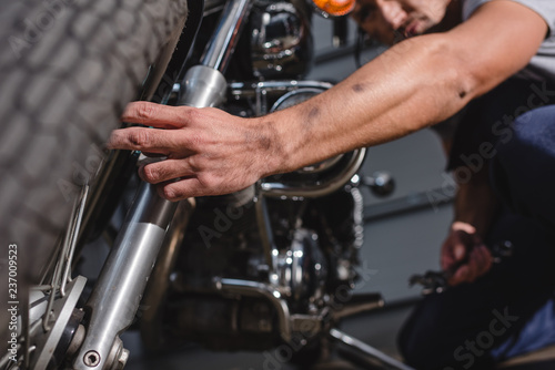 closeup of mechanic fixing motorbike front wheel in garage