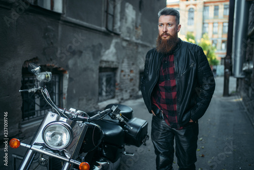 Bearded biker in leather clothes against chopper