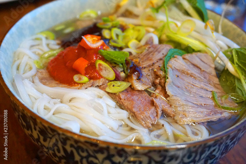 Vietnamese traditional food rice noodles with grilled pork spring onion, peanut, spring roll, lettuce, vegetable, carrot, Asian cuisine with chillies garlic fish sauce dipping sauce 