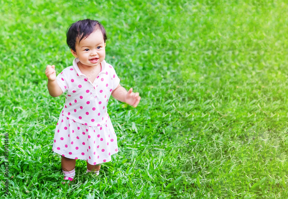 Closeup little girl stand on grass floor in the park with sun light background with copy space Closeup little girl stand on grass floor in the park with sun light background with copy space