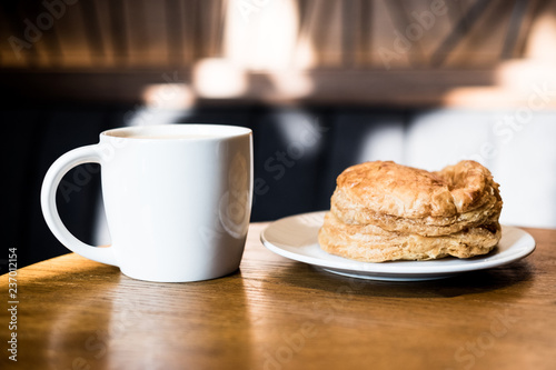 A cup of Coffee and whole cooked pie with a pair of mushrooms on wooden background