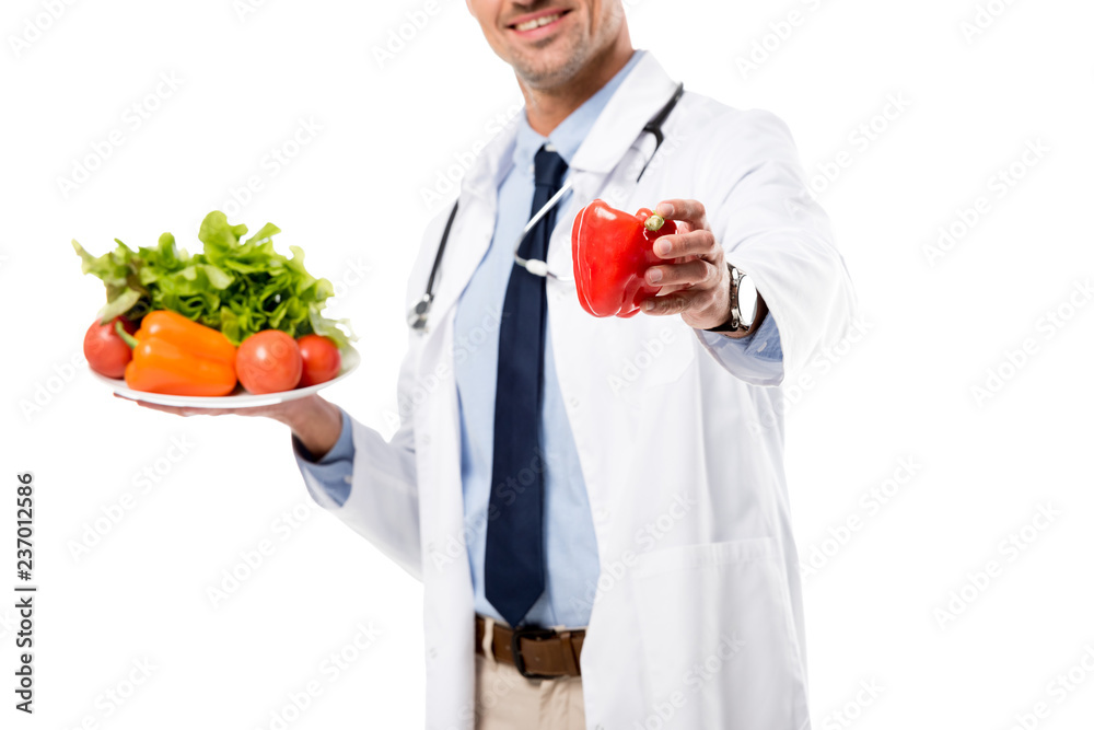 cropped view of doctor holding pepper and plate of fresh vegetables with greenery isolated on white, healthy eating concept cropped view of doctor holding pepper and plate of fresh vegetables with greenery isolated on white, healthy eating concept