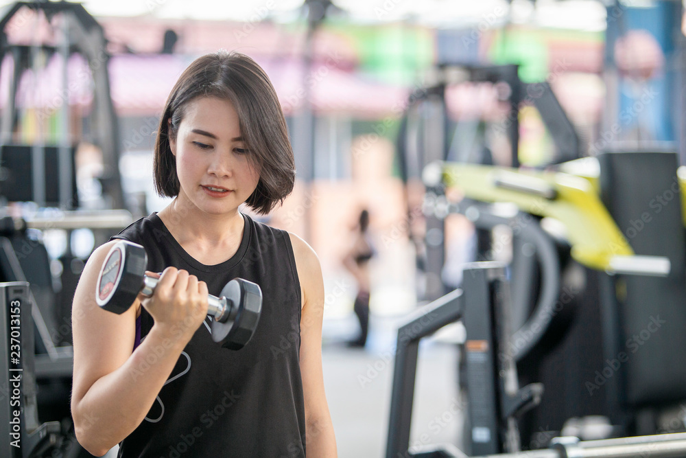 Fototapeta premium Asian woman training with dumbbells in the gym.