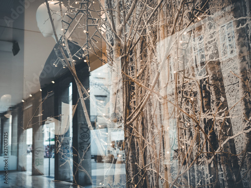 Rimini, italy, December 2018 maniquin is  shown on a clothing shop showcase. People walks for the street. Christmas atmosfere, Christmas showcase mounting. Double exposure. Reflections. Urban life. photo