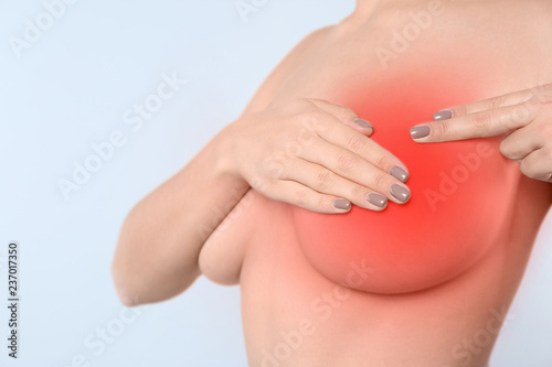 Woman doing breast self-examination on light background. Cancer awareness