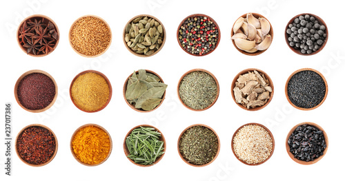Wooden bowls with different spices and herbs on white background, top view. Large collection