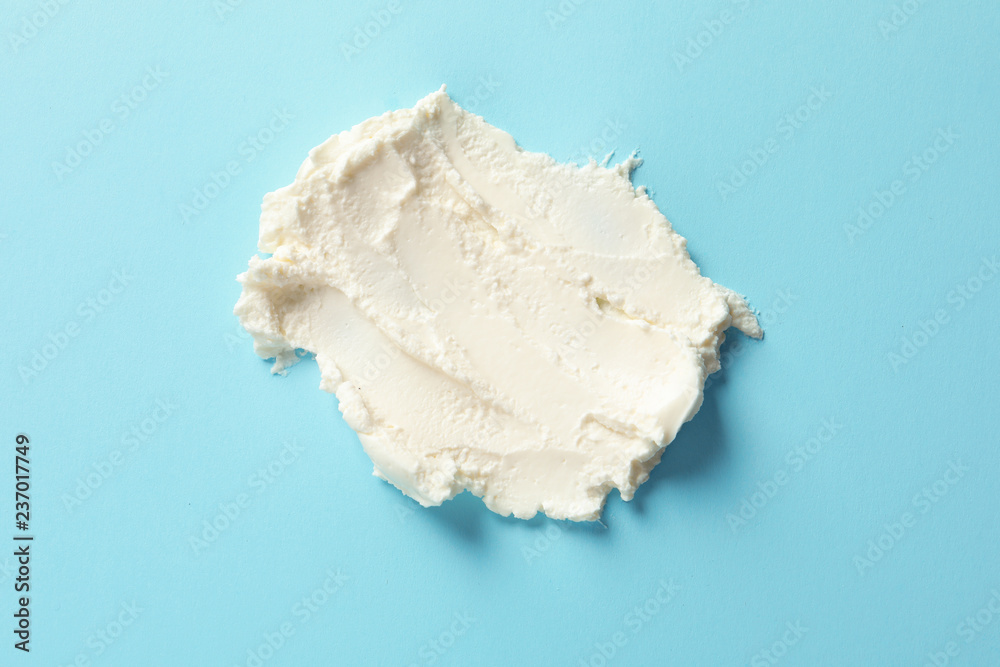 Smear of tasty cream cheese on color background, top view