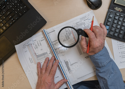 an architect, a white-haired man, 60 years old, works with project documentation at the table