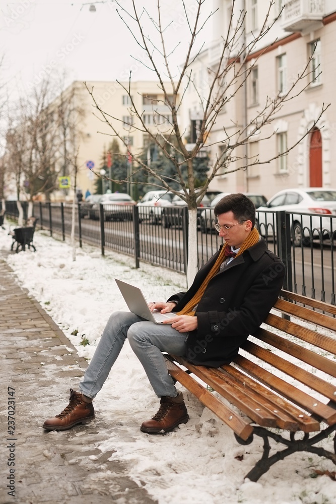 Business and freedom. Modern businessman, laptop keyboard with a laptop in nature, on a bench and working, winter