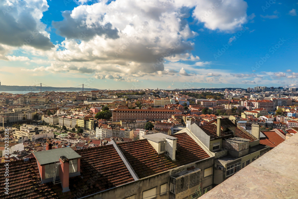 Partial view of the center of Lisbon, with the 25 de Abril bridge in the background, late afternoon, blue sky with clouds