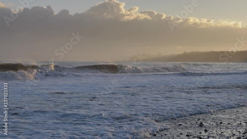 Waves and ocean spray crashing on the beach at sunrise. photo