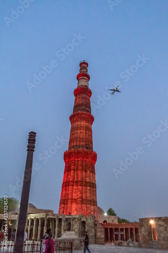 A pane flying past the Qutub Minar and the Iron Pillar of Delhi photo