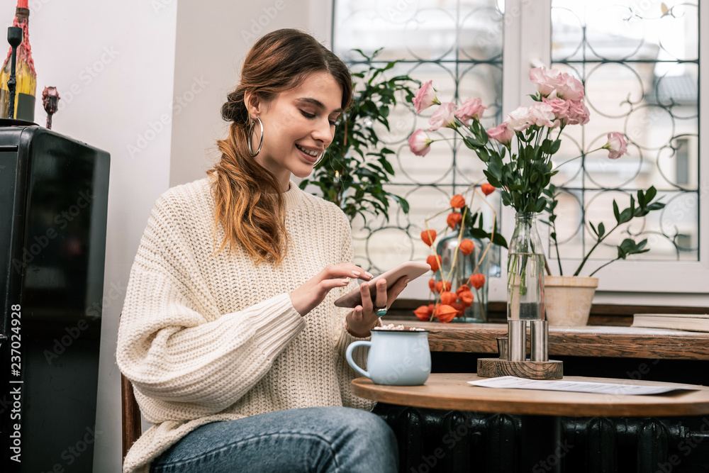 Woman surfing the internet using a smartphone while drinking cocoa Woman surfing the internet using a smartphone while drinking cocoa