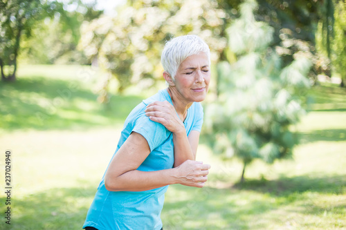 Senior sporty woman having shoulder pain