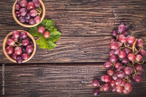 Red grapes on rustic wood background with copy space, top view, close-up.