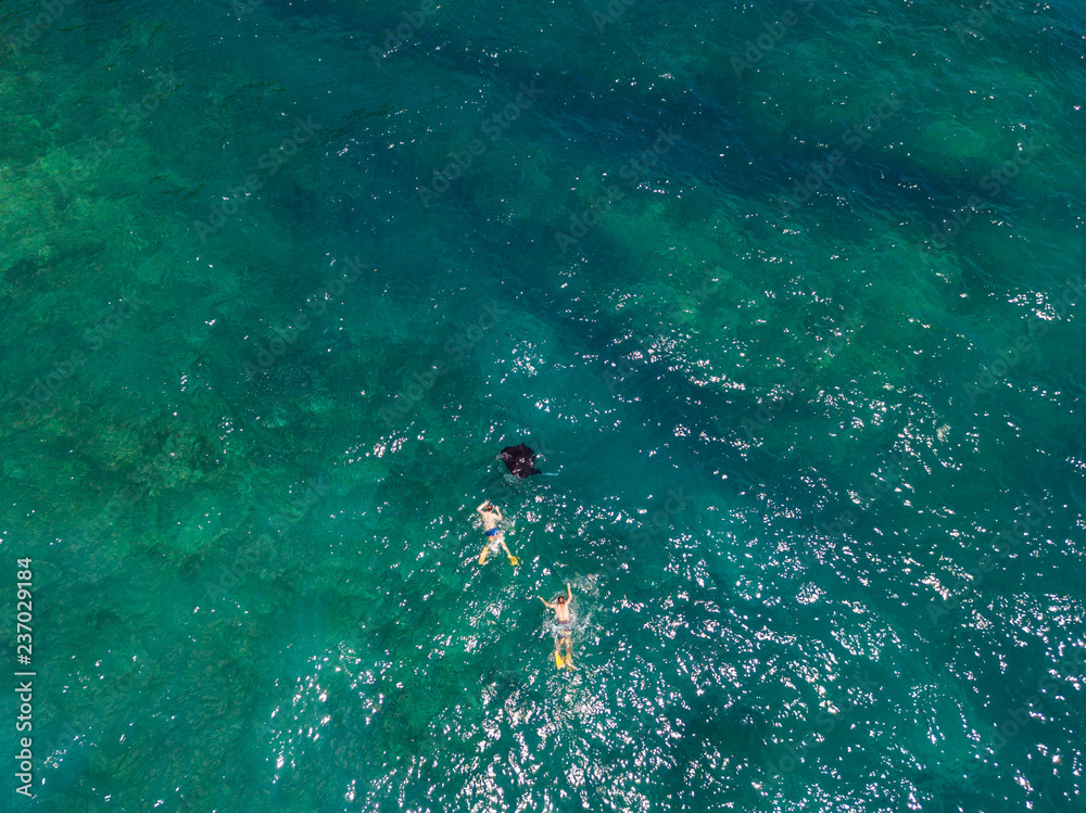 Aerial drone view of snorkelers with huge oceanic manta rays near Manta bay on Nusa Penida island.