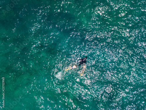 Aerial drone view of snorkelers with huge oceanic manta rays near Manta bay on Nusa Penida island.
