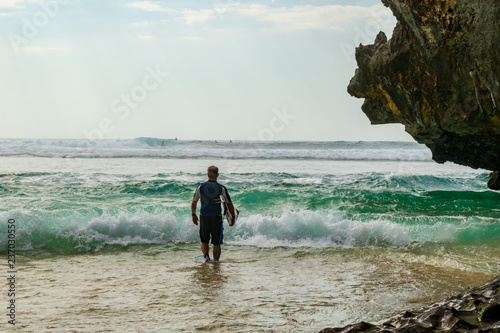 Suluban Beach- the beautiful hidden beach, a surfer heading out into the sea photo